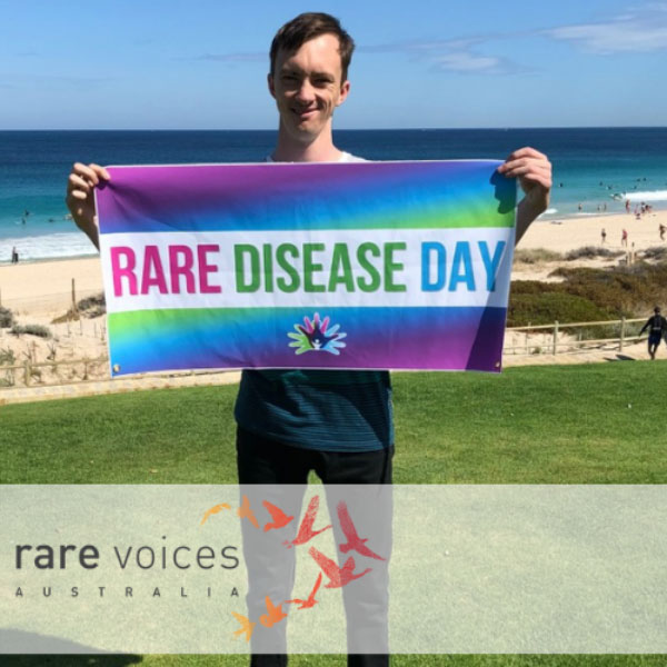Photo of Andrew holding the Rare Disease Day banner.