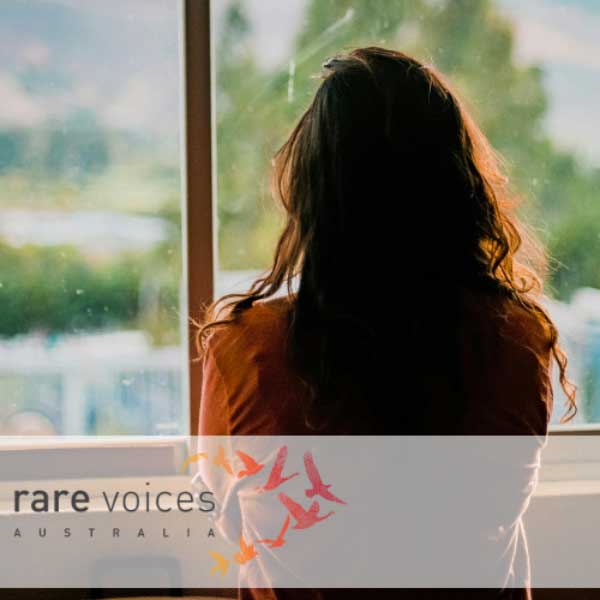 Image of a woman looking out the window with her back turned and arms crossed
